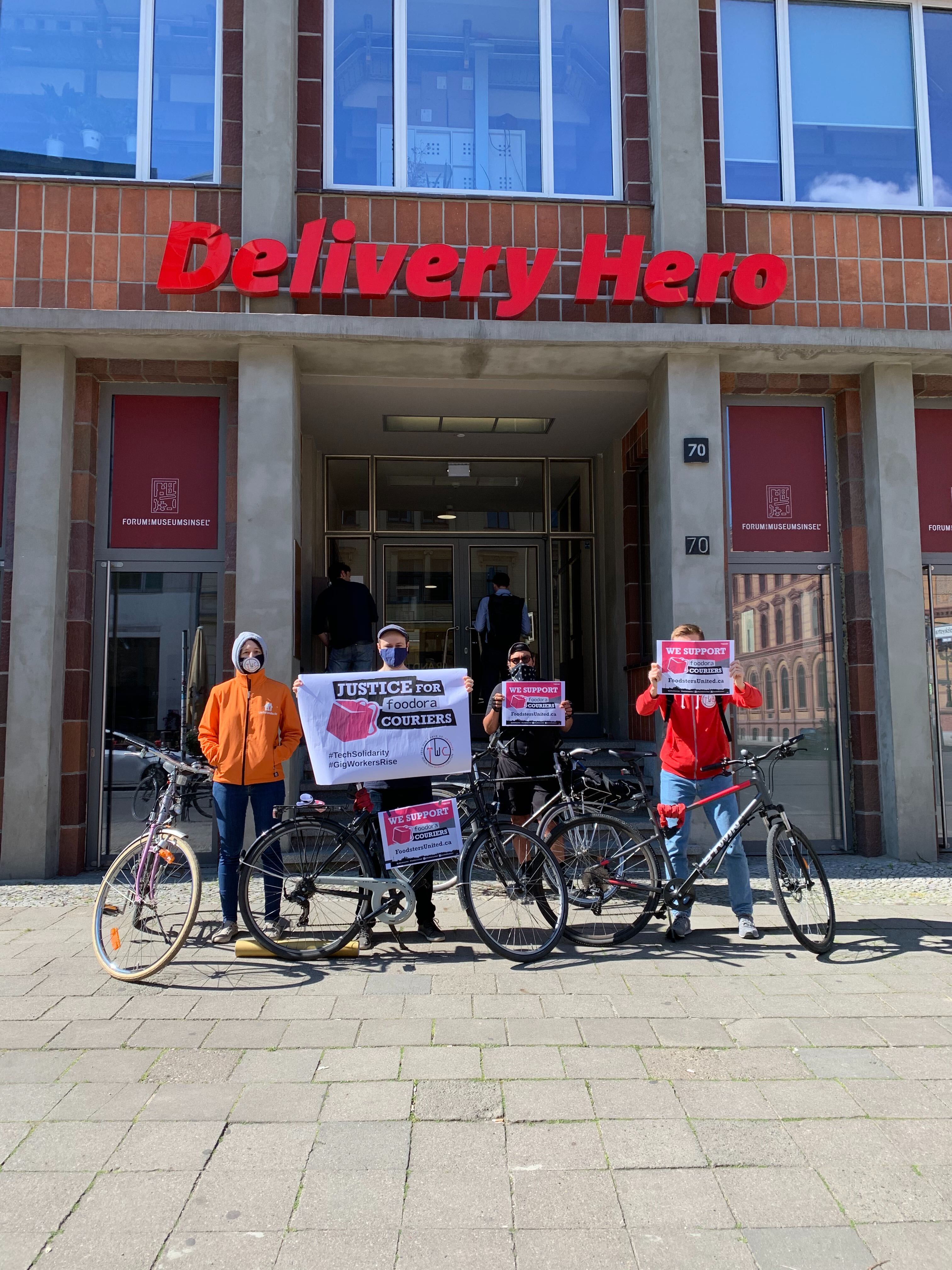 Group photo in front of Delivery Hero headquarters, wearing masks and holding signs